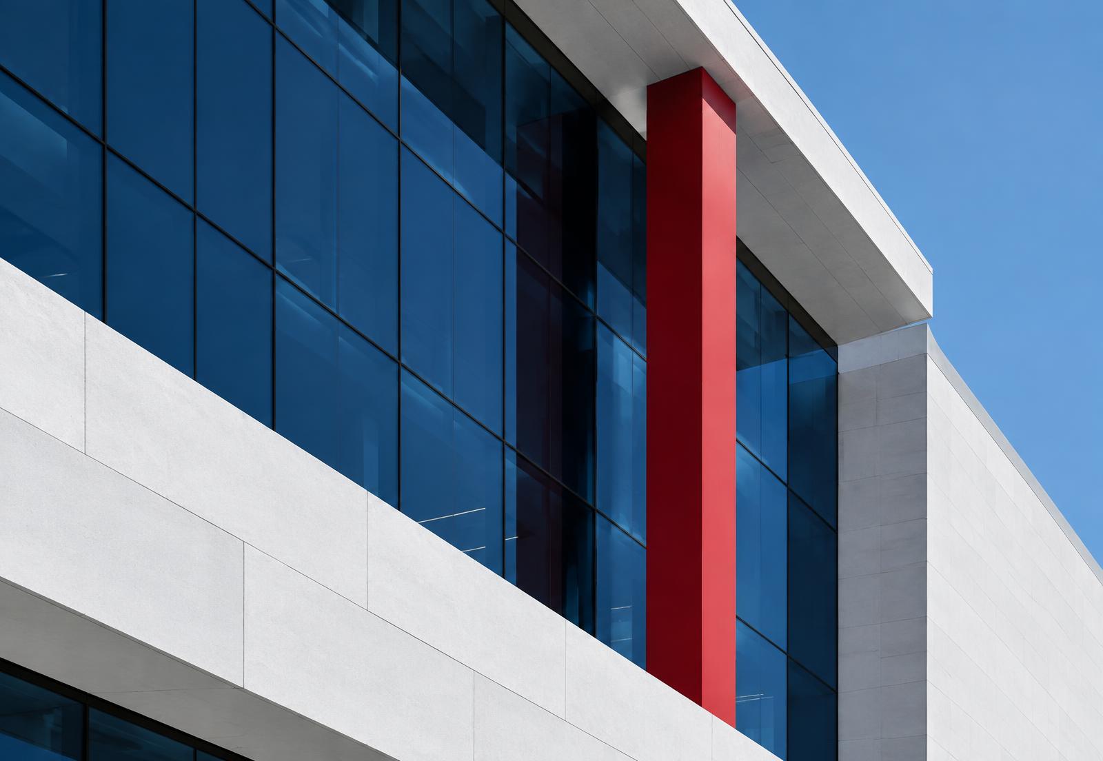 Modern Canadian architecture with navy glass, white stone, and a red column